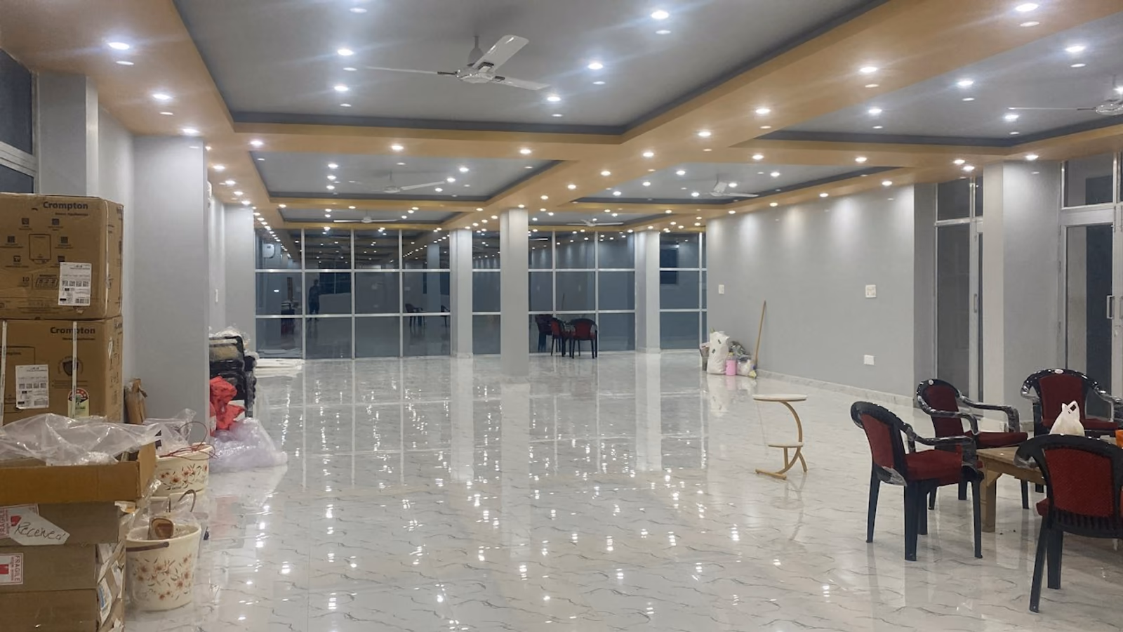 An empty wedding hall with boxes and plastic chairs